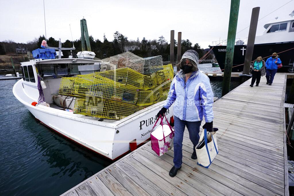 Robert F. Bukaty Nurse Sharon Daley carries a cooler of COVID-19 vaccinations as she and her staff begin a journey to inoculate island residents, Friday, March 19, 2021, in Northeast Harbor, Maine. (AP Photo/Robert F. Bukaty)