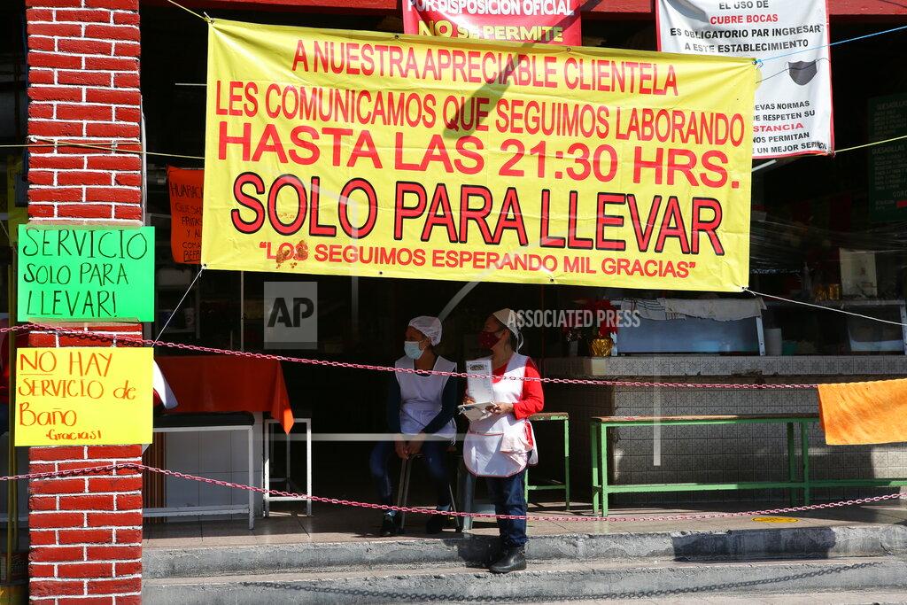 Ginnette Riquelme Restaurant workers wait for customers at a restaurant open only for take away service in Mexico City, Sunday, Dec. 20, 2020. After months of resisting to avoid hurting the economy, officials banned all non-essential activities starting Saturday and returned to a partial lockdown in Mexico City and the surrounding State of Mexico because of a spike in coronavirus cases that has crowded hospitals. (AP Photo/Ginnette Riquelme)
