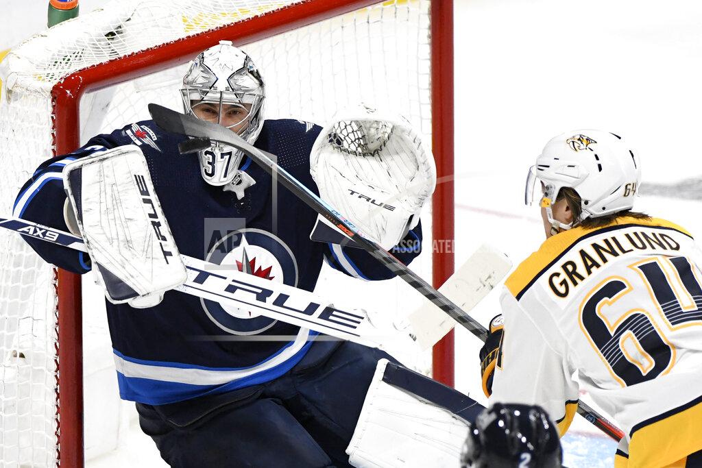 Fred Greenslade Winnipeg Jets goaltender Connor Hellebuyck (37) watches the puck as Nashville Predators' Mikael Granlund (64) reaches for it during the second period of NHL hockey game action in Winnipeg, Manitoba, Saturday, Oct. 23, 2021. (Fred Greenslade/The Canadian Press via AP)