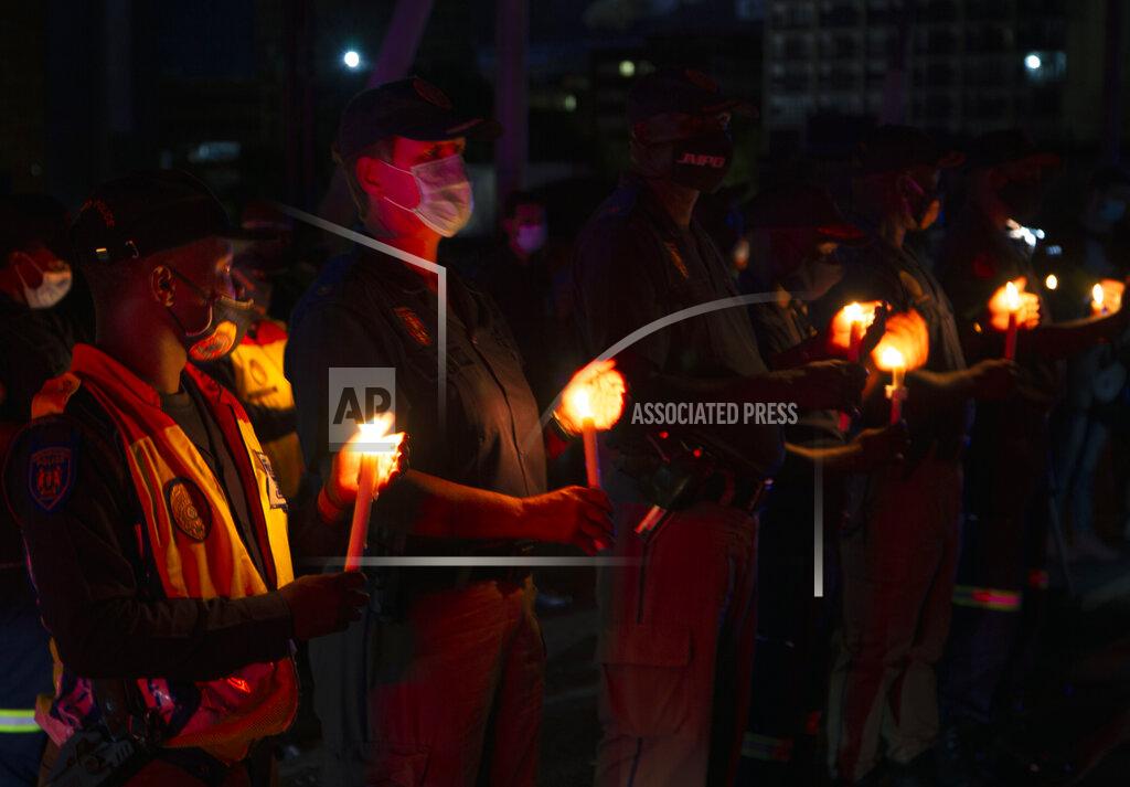 Denis Farrell Frontline workers attend a candlelight ceremony on New Year's Eve on the famed Nelson Mandela Bridge in downtown Johannesburg Thursday, Dec. 31, 2020. Many South Africans will swap firecrackers for candles to mark New Year's Eve amid COVID-19 restrictions including a nighttime curfew responding to President Cyril Ramaphosa's call to light a candle to honor those who have died in the COVID-19 pandemic and the health workers who are on the frontline of battling the disease.. (AP Photo/Denis Farrell)