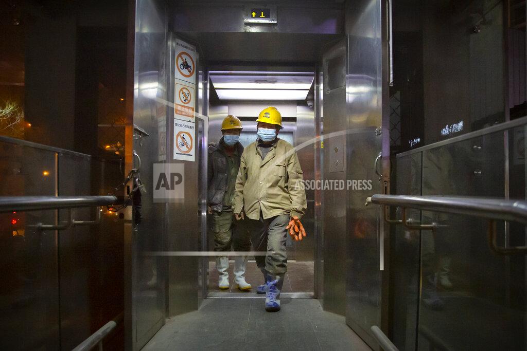 Mark Schiefelbein Construction workers wearing face masks to protect against the spread of the coronavirus exit an elevator in Beijing, Wednesday, Jan. 13, 2021. China is concentrating its pandemic prevention efforts in the rural areas as officials urge people to not travel home for the annual Lunar New Year festival, as the country combats its most serious latest outbreak of COVID-19 since the pandemic originally broke out in Wuhan a year ago. (AP Photo/Mark Schiefelbein)