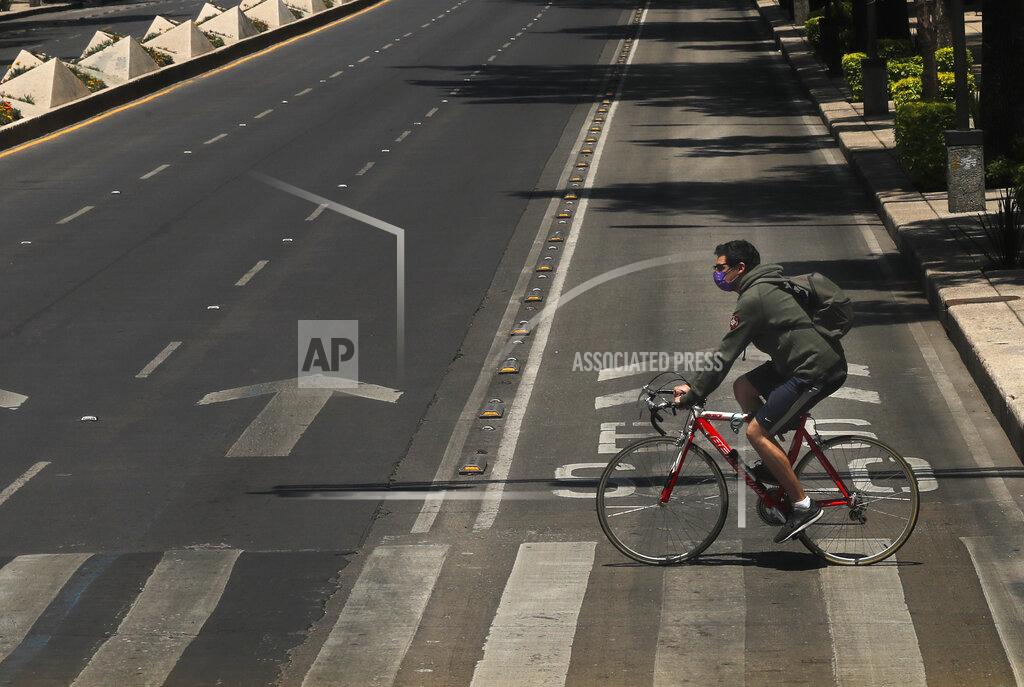 Marco Ugarte A cyclist wears a protective mask as a precaution against the spread of the new coronavirus as he crosses Mexico City's Reforma avenue, Monday, April 27, 2020. (AP Photo/Marco Ugarte)