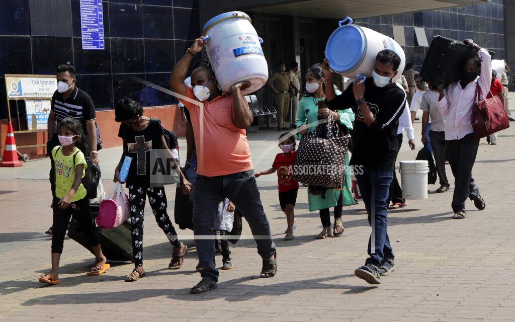 Rajanish Kakade People wearing masks as a precaution against the coronavirus walk to board trains at Lokmanya Tilak Terminus in Mumbai, India, Friday, April 16, 2021. Migrant workers are swarming rail stations in India's financial capital Mumbai to go to their home villages as virus-control measures dry up work in the hard-hit region. The government of Maharashtra state imposed lockdown-like curbs on Wednesday for 15 days to check the spread of the virus. It closed most industries, businesses and public places and limited the movement of people, but didn’t stop the bus, train and air services. An exodus ensued, with panicked day laborers hauling backpacks onto overcrowded trains leaving Mumbai, travel that raises fears of infections spreading in rural areas. (AP Photo/Rajanish Kakade)