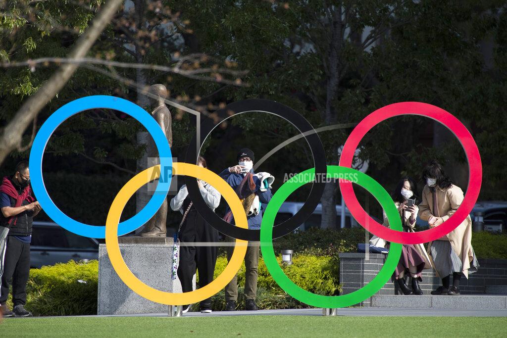 FILE - In this March 19, 2021, file photo, people take pictures of the Olympic rings installed by the Japan Olympic Museum in Tokyo. The vaccine rollout in Japan has been very slow with less than 1% vaccinated. This of course is spilling over to concerns about the postponed Tokyo Olympics that open in just over three months.(AP Photo/Hiro Komae, File)