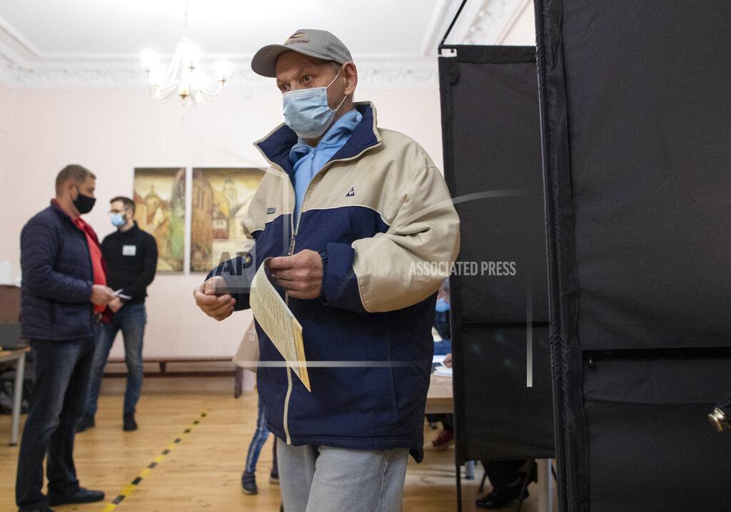 Mindaugas Kulbis A man, wearing face masks to protect against coronavirus leaves the polling booth at a polling station during parliamentary elections in Vilnius, Lithuania, Sunday, Oct. 11, 2020. Polls opened Sunday for the first round of national election in Lithuania, where voters will renew the 141-seat parliament and the ruling four-party coalition is widely expected to face a stiff challenge from the opposition to remain in office. (AP Photo/Mindaugas Kulbis)