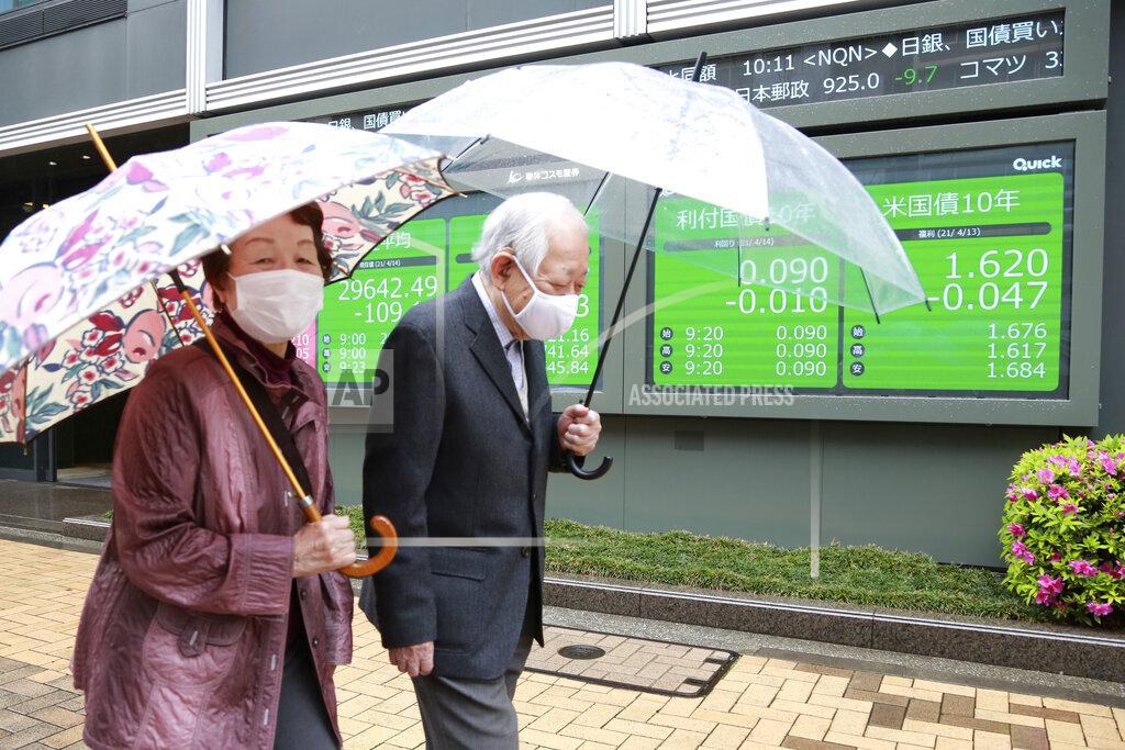 Koji Sasahara A couple wearing face masks walks by an electronic stock board of a securities firm in Tokyo, Wednesday, April 14, 2021. Asian stock markets rose Wednesday after Wall Street hit a high following an uptick in U.S. inflation and an order by regulators to suspend use of Johnson & Johnson's coronavirus vaccine. (AP Photo/Koji Sasahara)