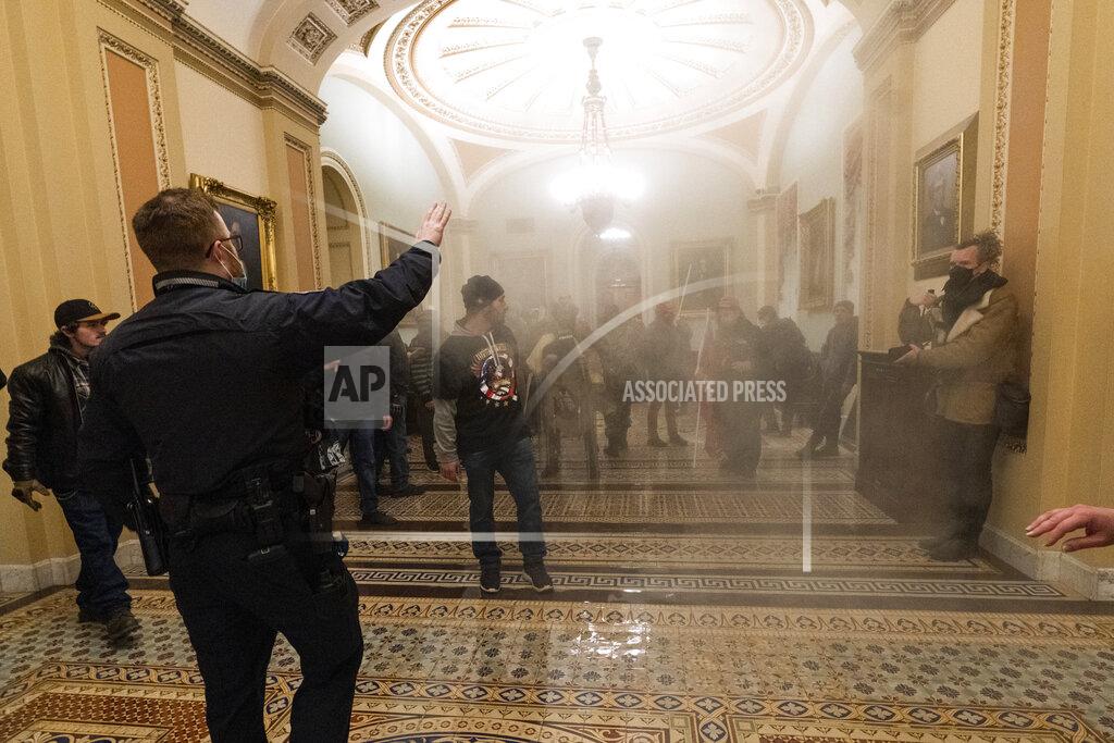 Manuel Balce Ceneta FILE - In this Wednesday, Jan. 6, 2021 file photo smoke fills the walkway outside the Senate Chamber as supporters of President Donald Trump are confronted by U.S. Capitol Police officers inside the Capitol in Washington. Right-wing extremism has previously mostly played out in isolated pockets of America or in smaller cities. In contrast, the deadly attack by rioters on the U.S. Capitol targeted the very heart of government. It brought together members of disparate groups, creating the opportunity for extremists to establish links with each other. (AP Photo/Manuel Balce Ceneta, File)