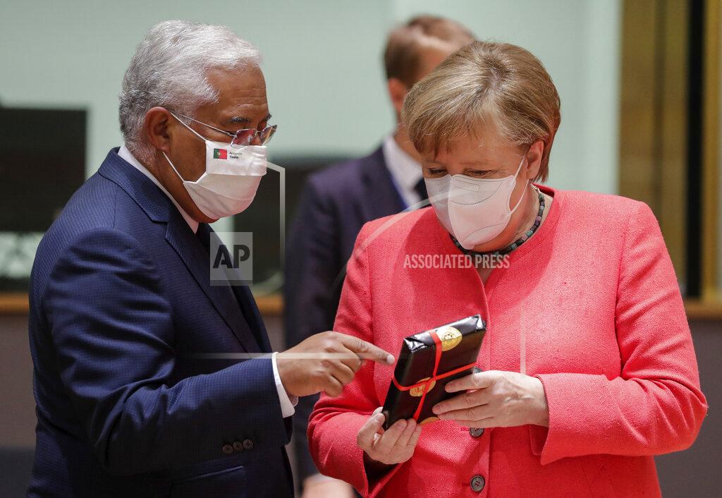 Stephanie Lecocq German Chancellor Angela Merkel, right, receives a gift from Portugal's Prime Minister Antonio Costa during a round table meeting at an EU summit in Brussels, Friday, July 17, 2020. Leaders from 27 European Union nations meet face-to-face on Friday for the first time since February, despite the dangers of the coronavirus pandemic, to assess an overall budget and recovery package spread over seven years estimated at some 1.75 trillion to 1.85 trillion euros. (Stephanie Lecocq, Pool Photo via AP)
