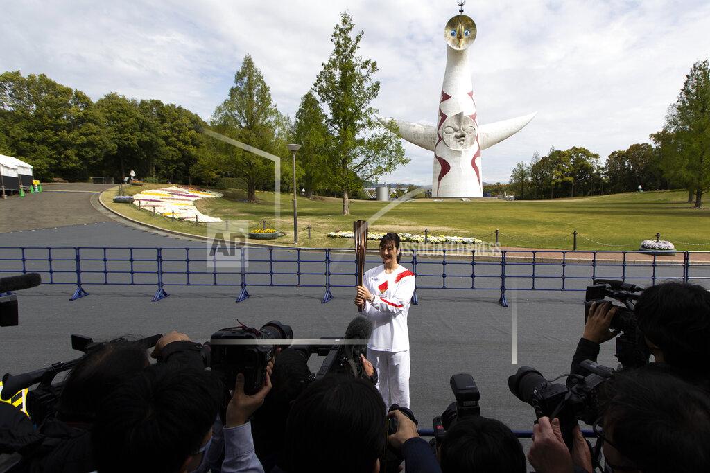 Former Olympian Aya Terakawa, participating as an Olympic torch relay runner, poses for the media before she carries the torch during the first day of the Osaka round at a former Expo site in Suita, north of Osaka, western Japan, Tuesday, April 13, 2021. The Tokyo 2020 Olympic kick-off event which was rescheduled due to the coronavirus outbreak was yet rearranged to hold at the former Expo park, instead of public streets, to close off the audience from the even, following the mayor's decision as Osaka has had sharp increases in daily cases since early March. (AP Photo/Hiro Komae)