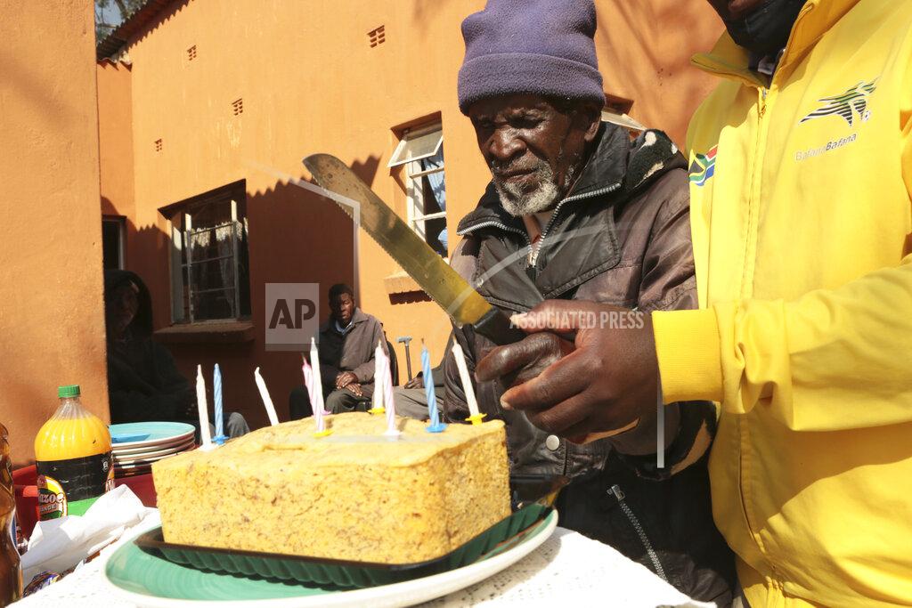 Tsvangirayi Mukwazhi A 103 year old man is helped to cut a banana bread cake during his birthday celebrations at Melfort Old People's home on the outskirts of Harare, Zimbabwe, Sunday, July 25, 2021. The economic ravages of COVID-19 are forcing some families in Zimbabwe to abandon the age old tradition of taking care of the elderly. Zimbabwe's care homes have experienced a 60% increase in admissions since the outbreak of the pandemic in March last year. (AP Photo/Tsvangirayi Mukwazhi)