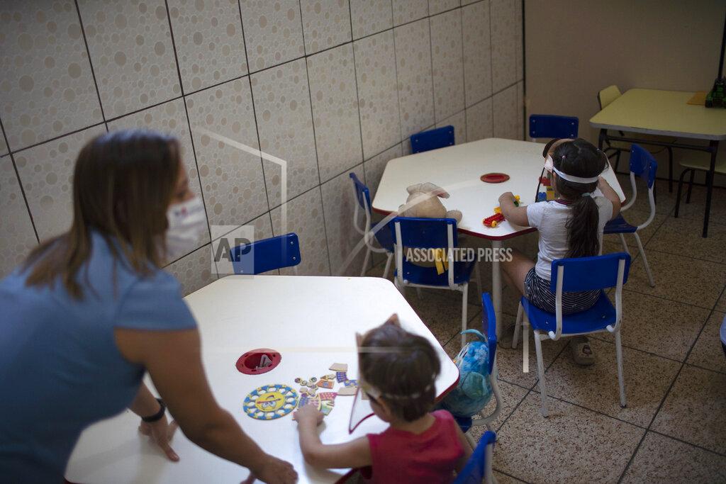 Silvia Izquierdo Children wearing face shields as a precaution against the new coronavirus outbreak sit spaced apart in individual tables at the Pereira Agustinho daycare, nursery school and pre-school, after it reopened amid the new coronavirus pandemic in Duque de Caxias, Monday, July 6, 2020. The city of Manaus in the Amazon rainforest and Duque de Caxias in Rio de Janeiro’s metropolitan region, became on Monday the first Brazilian cities to resume in-person classes at private schools since the onset of the COVID-19 pandemic, according to the nation's private school federation. (AP Photo/Silvia Izquierdo)