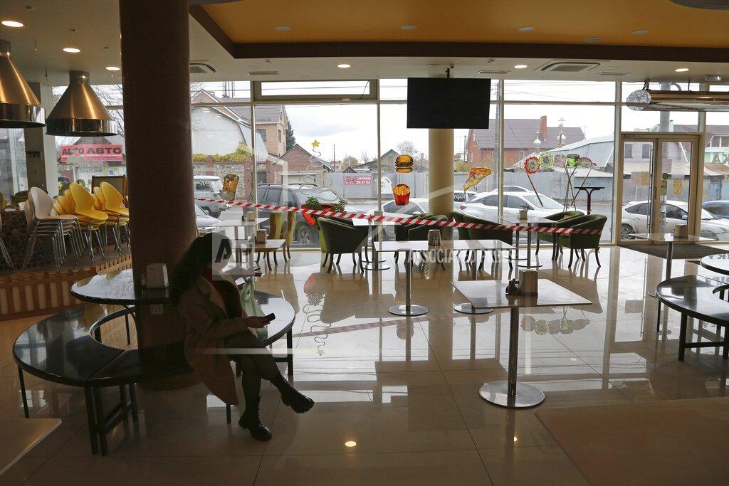 Yuri Strelets A woman sits inside a cafe closed due to a spike in coronavirus cases in Samara, Russia, Monday, Oct. 25, 2021. The Samara region was one of the first of Russia's 85 regions to enter a nonworking period Monday, a measure ordered by the Kremlin to stem the spread of infection as the country faced a spike in contagion. (AP Photo/Yuri Strelets)