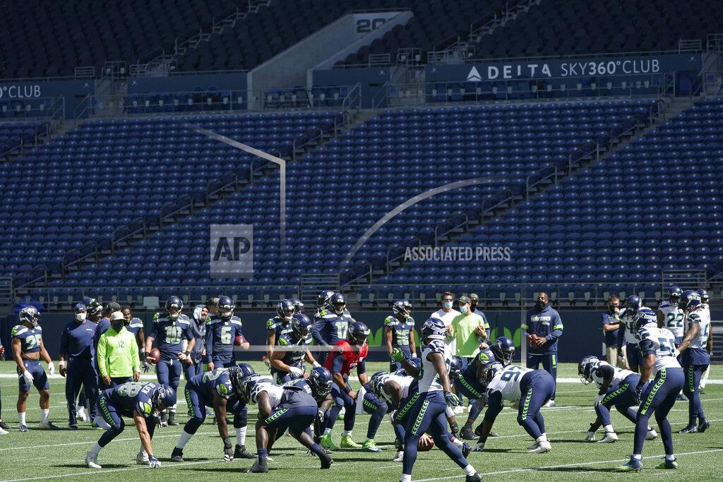 Ted S. Warren Seattle Seahawks quarterback Russell Wilson, center, waits for the snap during warmups in front of empty seats at CenturyLink Field before an NFL football mock game, Wednesday, Aug. 26, 2020, in Seattle. (AP Photo/Ted S. Warren)