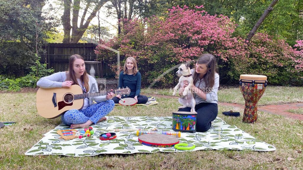 In this April 10, 2020 image from video, music therapists for St. Jude Children’s Research Hospital, from left, Celeste Douglas, intern Abigail Parrish and Amy Love record a session in Love’s backyard in Memphis, Tennessee. The group uploads their weekly sessions to YouTube so patients can continue receiving bedside music therapy. (Courtesy of Bryan Piras via AP)