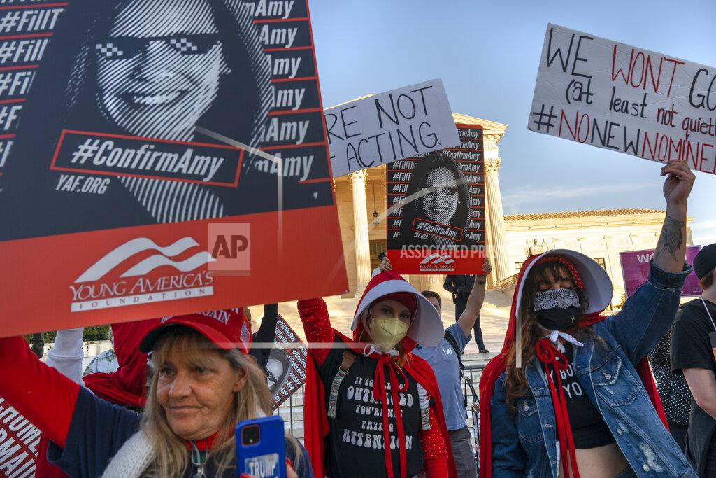 Jacquelyn Martin Jennifer Friend of Gainesville, Fla., left, rallies in favor of the nomination of Amy Coney Barrett to the Supreme Court, next to Sydney Hopfer, and Deidra Hubay, right, both of Pittsburgh, who oppose it, outside the Supreme Court, Monday, Oct. 26, 2020, on Capitol Hill in Washington. (AP Photo/Jacquelyn Martin)