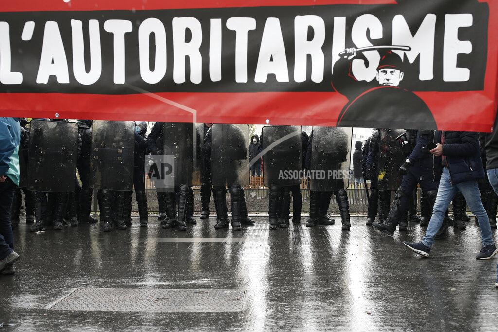 Lewis Joly Riot police officers stand behind a banner reading "authoritarianism" during May Day demonstration, Saturday, May 1, 2021 in Paris. Workers and union leaders dusted off bullhorns and flags that had stayed furled during coronavirus lockdowns for slimmed down but still boisterous May Day marches on Saturday, demanding more labor protections amid a pandemic that has turned economies and workplaces upside down. (AP Photo/Lewis Joly)