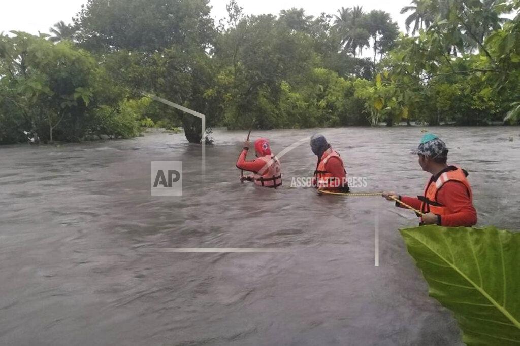 Uncredited In this photo provided by the Philippine Coast Guard, members of the Philippine coastguard wade along floodwaters as the look for residents to be evacuated to safer grounds, in Naujan, Oriental Mindoro province, central Philippines on Friday July 23, 2021. Thousands of residents fled from flooded communities and swollen rivers in the Philippine capital and outlying provinces Saturday after days of torrential monsoon rains, which left at least one villager dead, officials said. (Philippine Coast Guard via AP)