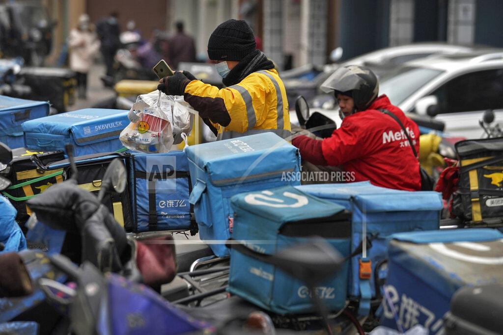 Andy Wong A food delivery worker wearing a face mask to help curb the spread of the coronavirus prepares to deliver foods for his customers outside a restaurant in Beijing on Thursday, Jan. 14, 2021. The e-commerce workers and delivery people who kept China fed during the pandemic, making their billionaire bosses even richer, are so unhappy with their pay and treatment that one just set himself on fire in protest. (AP Photo/Andy Wong)