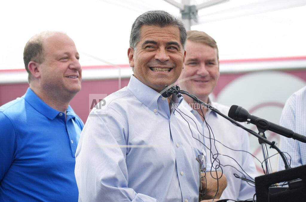 David Zalubowski U.S. Department of Health and Human Services Secretary Xavier Becerra, center, speaks accompanied by Colorado Gov. Jared Polis, left, and U.S. Sen. Michael Bennet, D-Colo., during a visit to a pair of buses set up as traveling clinics as part of the state's "Vaccines For All" campaign Friday, June 18, 2021, in Aurora, Colo. The buses are being used to distribute the COVID-19 vaccines. (AP Photo/David Zalubowski)