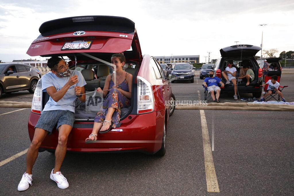 Ryan Fleischer, left, and Angelisa Diveny prepare their car for a drive-in movie screening of the film "Yesterday," Wednesday, July 8, 2020, in a parking lot behind the Boston Convention and Exhibition Center, in Boston. Access to the free July Drive-in Movie Series put on by the city is granted to Boston residents only. (AP Photo/Steven Senne)