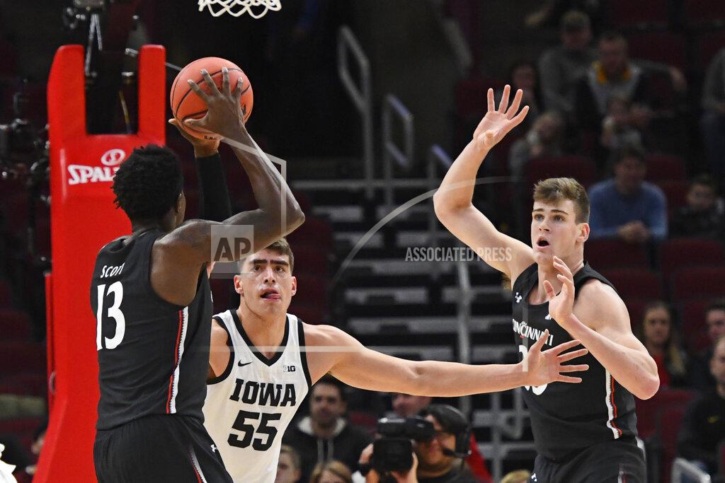 Matt Marton Cincinnati forward Tre Scott (13) passes the ball to center Chris Vogt, right, as Iowa center Luka Garza (55) defends during the first half of an NCAA college basketball game Saturday, Dec. 21, 2019, in Chicago. (AP Photo/Matt Marton)