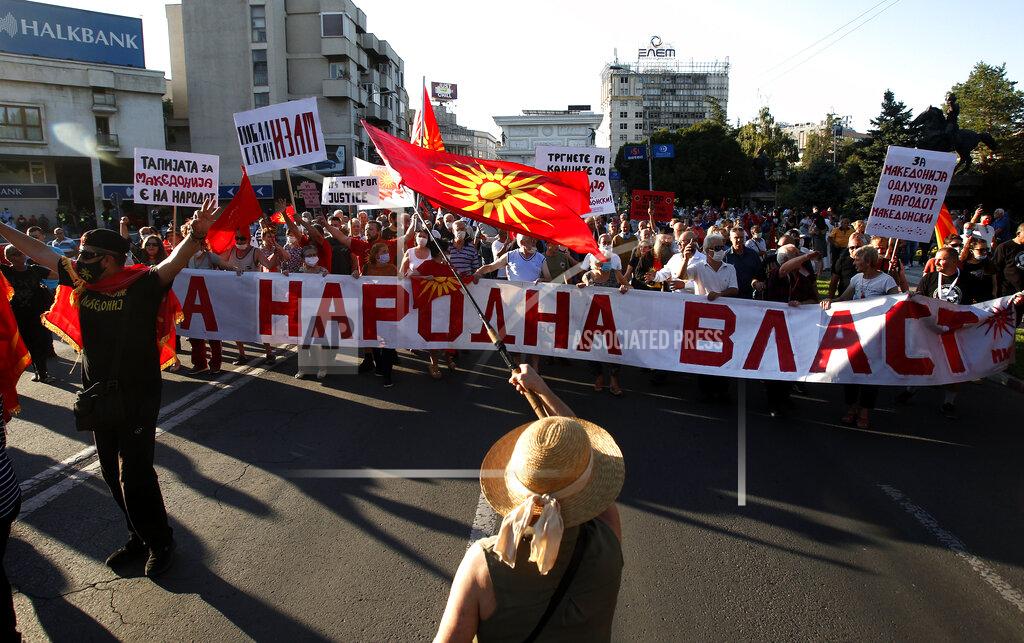 Boris Grdanoski People wave the old national flags and carry banners with patriotic slogans, protesting the change of country's name to North Macedonia and "disparage" of the Macedonian national identity and dignity in a process of country's Euro-Atlantic integration, in front of the parliament building in Skopje, North Macedonia, Sunday, Aug. 30, 2020. North Macedonia’s parliament continued its debate on a vote of confidence for a new left-wing coalition government after the Social Democrats and their ethnic Albanian partners secured a majority in parliament in July's general election. (AP Photo/Boris Grdanoski)