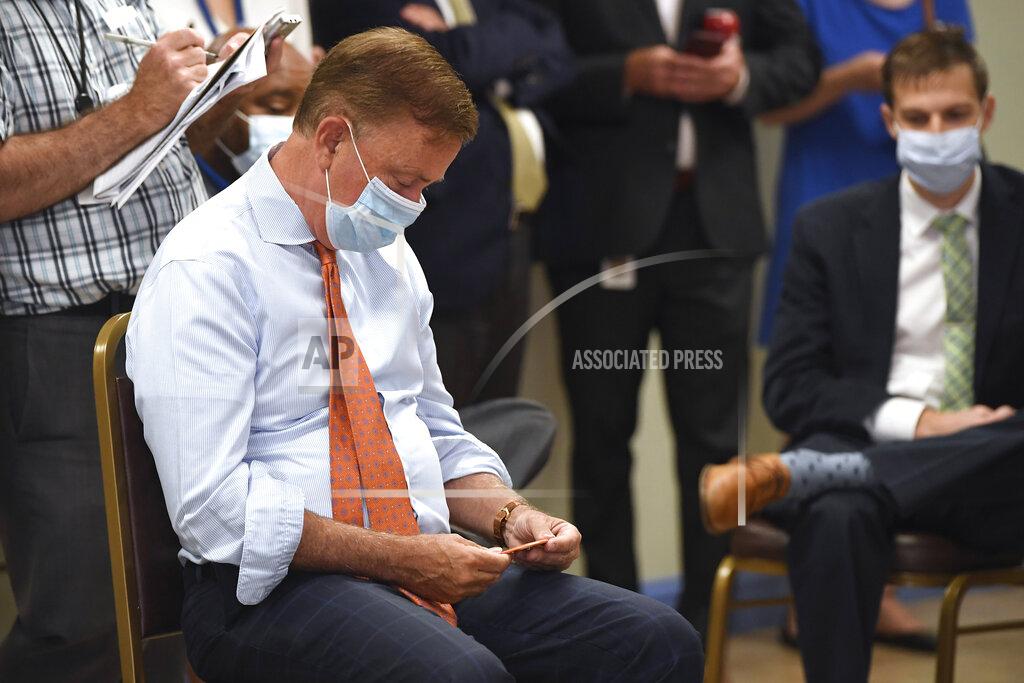 Jessica Hill Connecticut Gov. Ned Lamont looks at Connecticut Against Gun Violence button he was given before signing a ceremonial bill on gun safety at Hartford Communities That Care, Tuesday, July 27, 2021 in Hartford, Conn. (AP Photo/Jessica Hill)
