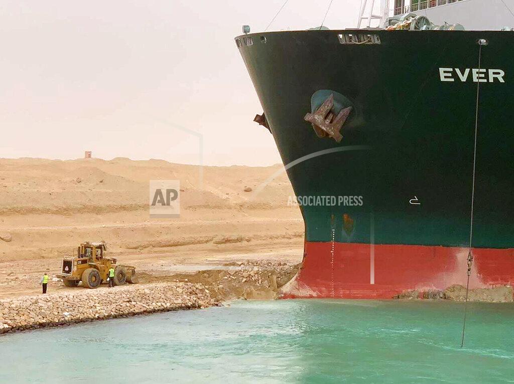 Uncredited CORRECTS NAME OF SHIP TO EVER GIVEN, NOT EVER GREEN - In this photo released by the Suez Canal Authority, a cargo ship, named the Ever Given, sits with its bow stuck into the wall Wednesday, March 24, 2021, after it become wedged across Egypt’s Suez Canal and blocked all traffic in the vital waterway. An Egyptian official warned Wednesday it could take at least two days to clear the ship. (Suez Canal Authority via AP)