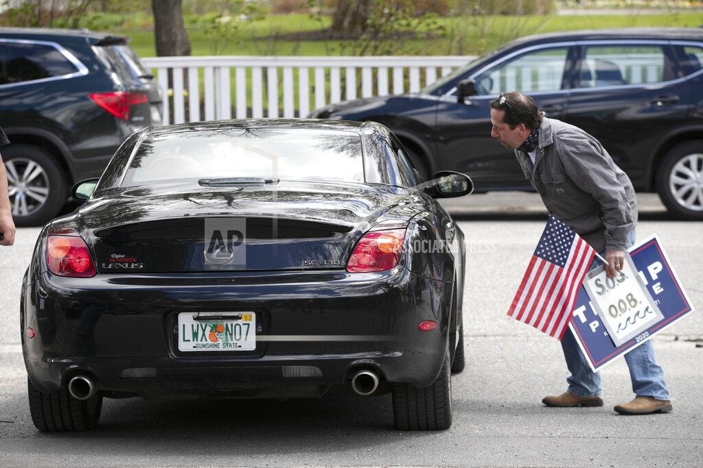 Robert F. Bukaty A man speaks to former Gov. Paul LePage, sitting in a Lexus SC 430, near a rally against the executive orders by Gov. Janet Mills to keep some Maine businesses closed to help prevent the spread of coronavirus, Saturday, May 16, 2020, in Augusta, Maine. A speaker at the event said the former governor, now a Florida resident, stayed in his car because he was quarantining. (AP Photo/Robert F. Bukaty)