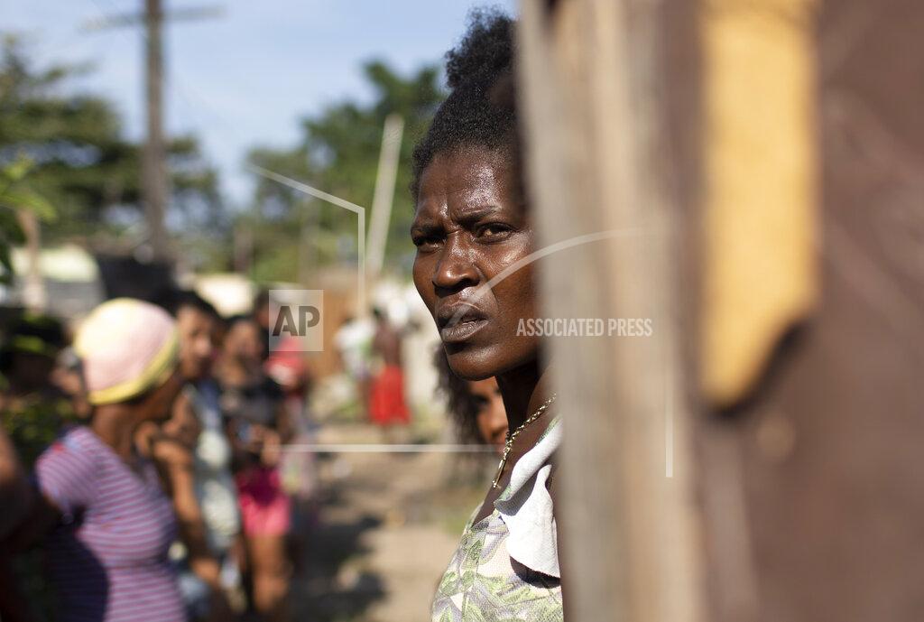 Silvia Izquierdo Gracieli Lima, 34, waits for food donated by the Covid Without Hunger program in the Jardim Gramacho slum of Rio de Janeiro, Brazil, Saturday, May 22, 2021. The federal government withdrew the welfare lifeline at the end of 2020, then resumed payments in April, but for only two-thirds as many people, who now receive less than half the previous monthly amounts. (AP Photo/Silvia Izquierdo, File)