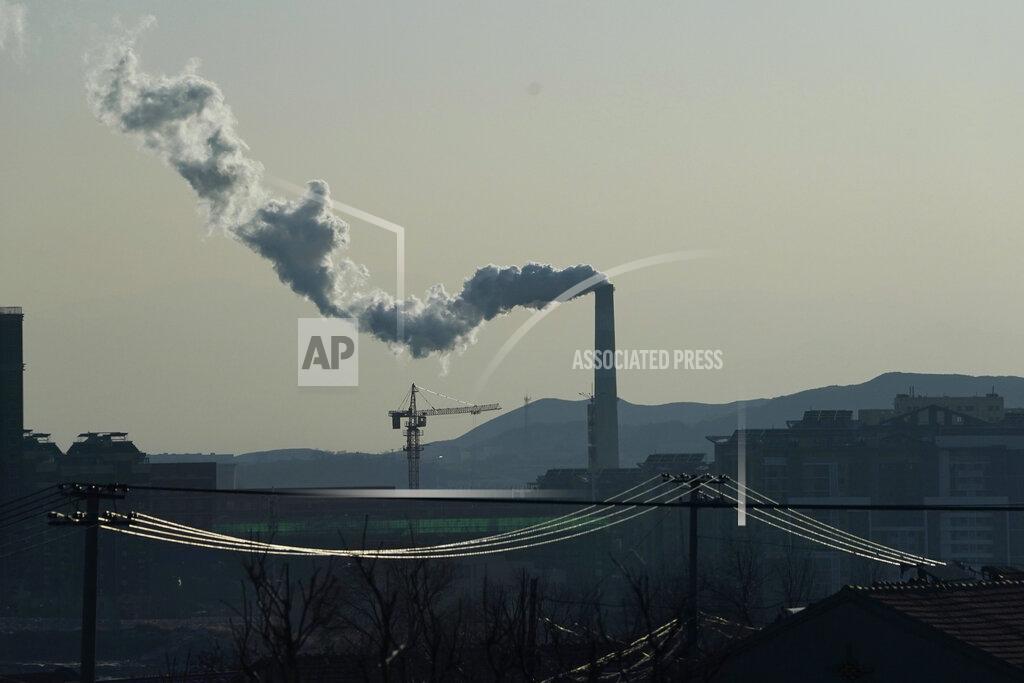 Ng Han Guan Smoke comes out of a chimney near cables from a high speed train traveling from Beijing to neighboring Zhangjiakou in northwestern China's Hebei province on Dec. 15, 2020. Expectations are high that the 14th five-year plan will align domestic policies with international pledges on climate change. Chinese President Xi Jinping made a surprise pledge at a United Nations meeting in September that China would go carbon neutral by 2060. (AP Photo/Ng Han Guan)