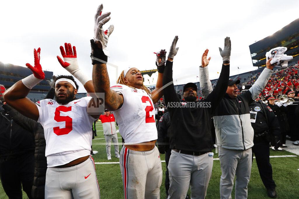 Paul Sancya FILE - In this Nov. 30, 2019, file photo, Ohio State's Baron Browning (5), Chase Young (2), linebackers coach Al Washington and head coach Ryan Day celebrate after a victory over Michigan in an NCAA college football game in Ann Arbor, Mich. Across the country universities have begun the process of playing through a pandemic. As athletes return to campus, what are they signing up for? Ohio State and Missouri have pledges they are requiring athletes or their parents sign before the players can take part in voluntary workouts at team facilities. (AP Photo/Paul Sancya, File)