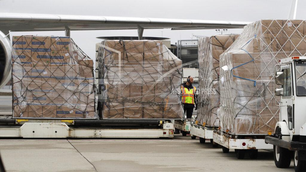 A ground crew worker looks on as over 110,000 pounds of personal protective equipment (PPE) from Shanghai, China, delivered to protect medical workers and first responders fighting the COVID-19 coronavirus outbreak, is unloaded from a cargo plane at Manchester-Boston Regional Airport in Manchester, New Hampshire, Thursday, April 30, 2020. (AP Photo/Charles Krupa)