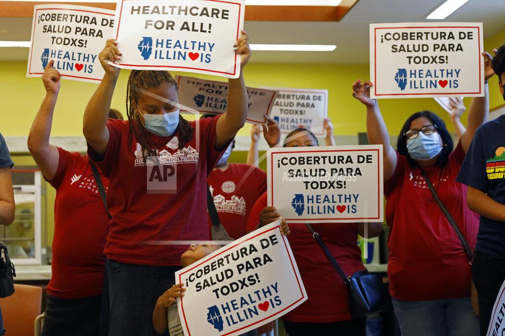 Shafkat Anowar Members of Health Illinois coalition celebrate the extension of state health insurance coverage to older immigrants, ages 55 and over, living in the country illegally, Tuesday, July 20, 2021, in Chicago's Pilsen neighborhood. The state was the first nationwide to offer a Medicaid-like program for immigrant seniors last year and used this year's budget to expand the program. (AP Photo/Shafkat Anowar)