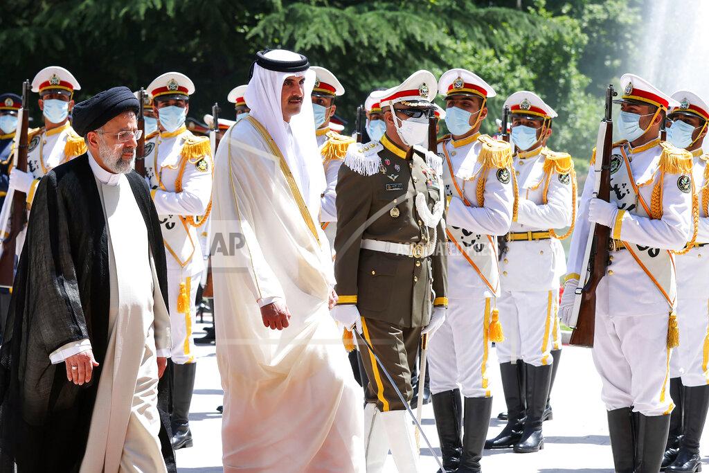 Uncredited In this photo released by the official website of the office of the Iranian Presidency, Qatari Emir Sheikh Tamim bin Hamad Al Thani, second left, reviews an honor guard as he is welcomed by President Ebrahim Raisi, left, during an official arrival ceremony at the Saadabad Palace in Tehran, Iran, Thursday, May 12, 2022. Qatar's emir arrived in Tehran for talks with the Iranian president as efforts to save Tehran's tattered nuclear deal with world powers hit a deadlock. (Iranian Presidency Office via AP)
