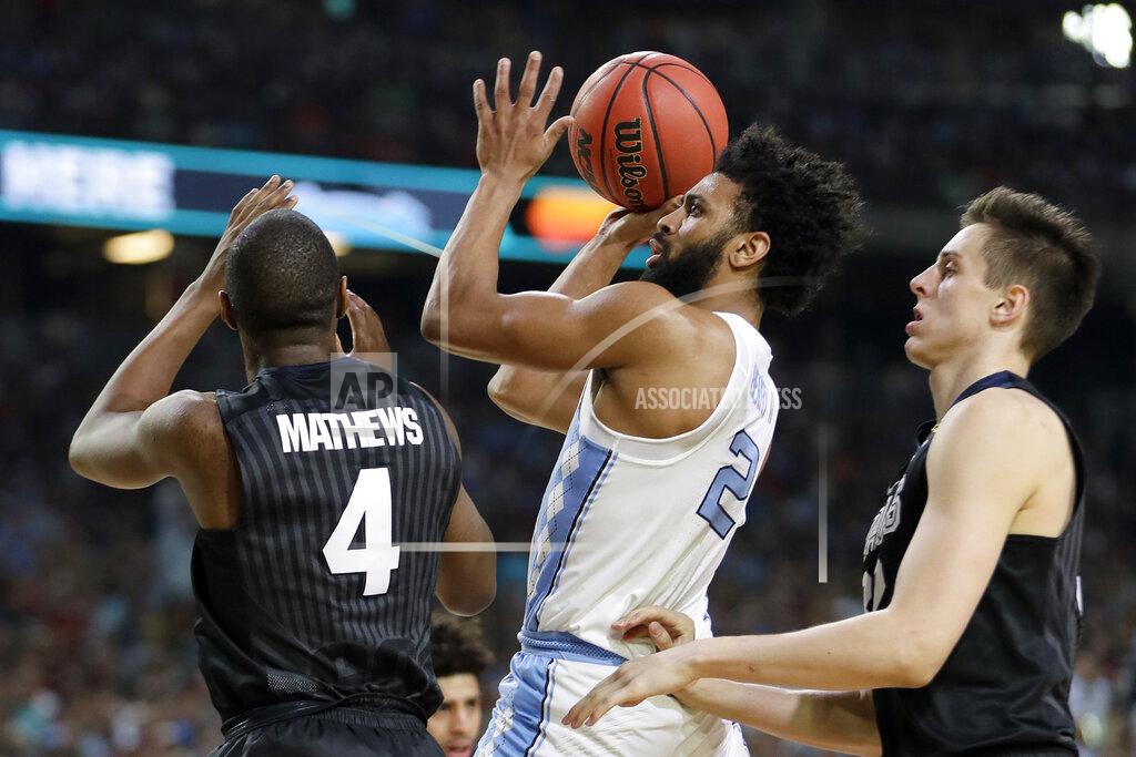 Mark Humphrey FILE - In this April 3, 2017, file photo, North Carolina's Joel Berry (2) takes a shot between Gonzaga's Jordan Mathews (4) and Zach Collins during the first half in the finals of the Final Four NCAA college basketball tournament, in Glendale, Ariz. North Carolina defeated Gonzaga 71-65. Berry was named MVP. (AP Photo/Mark Humphrey, File)