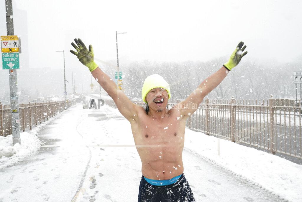 Kathy Willens Daniel Jun, who was running shirtless in a winter snowstorm, exhilarates as snowflakes continue to fall at a rapid pace, Sunday, Feb. 7, 2021, on the entrance to the Brooklyn Bridge in New York. (AP Photo/Kathy Willens)