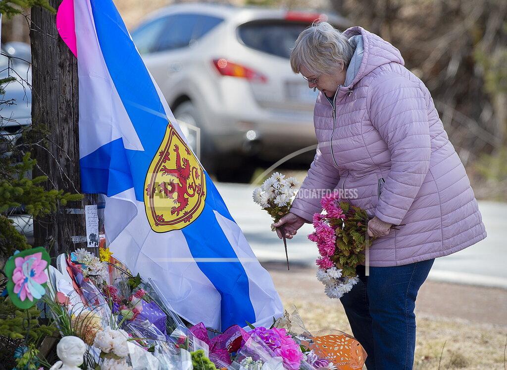 Andrew Vaughan A woman pays her respects at a roadside memorial in Portapique, Nova Scotia on Thursday, April 23, 2020. Royal Canadian Mounted Police say multiple people are dead after a man who at one point wore a police uniform and drove a mock-up cruiser, went on a murder rampage in Portapique and several other Nova Scotia communities. (Andrew Vaughan/The Canadian Press via AP)