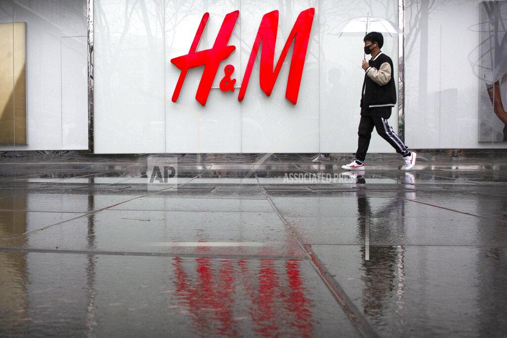 Mark Schiefelbein A man carrying an umbrellas walks past an H&M clothing store at a shopping mall in Beijing, Friday, March 26, 2021. H&M disappeared from the internet in China as the government raised pressure on shoe and clothing brands and announced sanctions Friday against British officials in a spiraling fight over complaints of abuses in the Xinjiang region. (AP Photo/Mark Schiefelbein)
