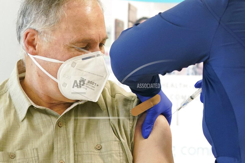 Ted S. Warren Washington Gov. Jay Inslee, left, gets the first shot of the Moderna COVID-19 vaccine, Friday, Jan. 22, 2021, from Elizabeth Smalley, right, a medical assistant at a Sea Mar Community Health Center in Olympia, Wash. Inslee's wife Trudi also received the first dose of the vaccine. (AP Photo/Ted S. Warren)
