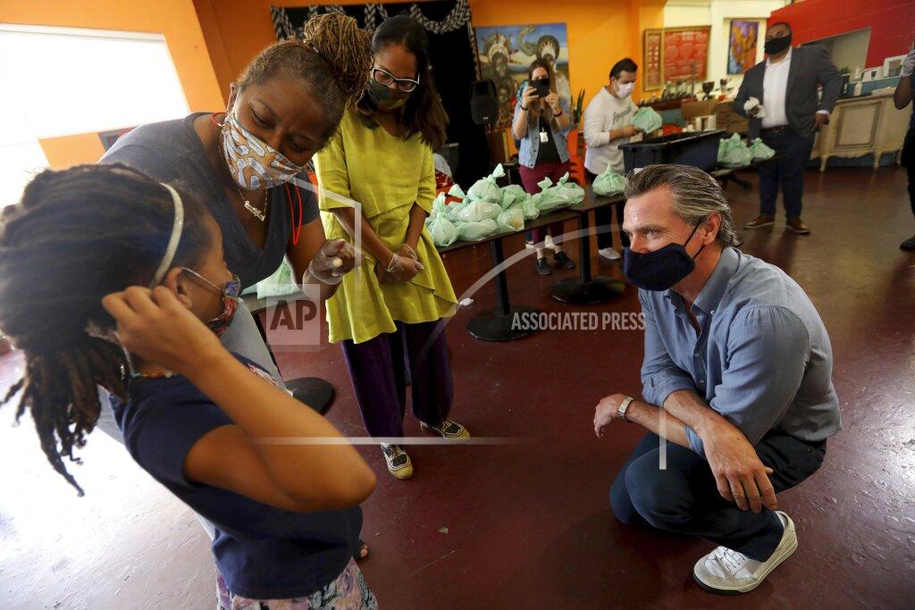 Genaro Molina California Gov. Gavin Newsom, right, listens as he is introduced to Kirikou Muldrow, 8, by California Senator Holly Mitchell and California Assembly Member Sydney Kamlager-Dove, right, during a visit to the Hot and Cool Cafe in Leimert Park in Los Angeles on Wednesday, June 3, 2020. The cafe has been providing meals prepared at the establishment three days a week for older adults during the coronavirus pandemic stay at home order. Muldrow has been helping pack the meals. Her mother is co-owner of the the cafe. (Genaro Molina/Los Angeles Times via AP, Pool)