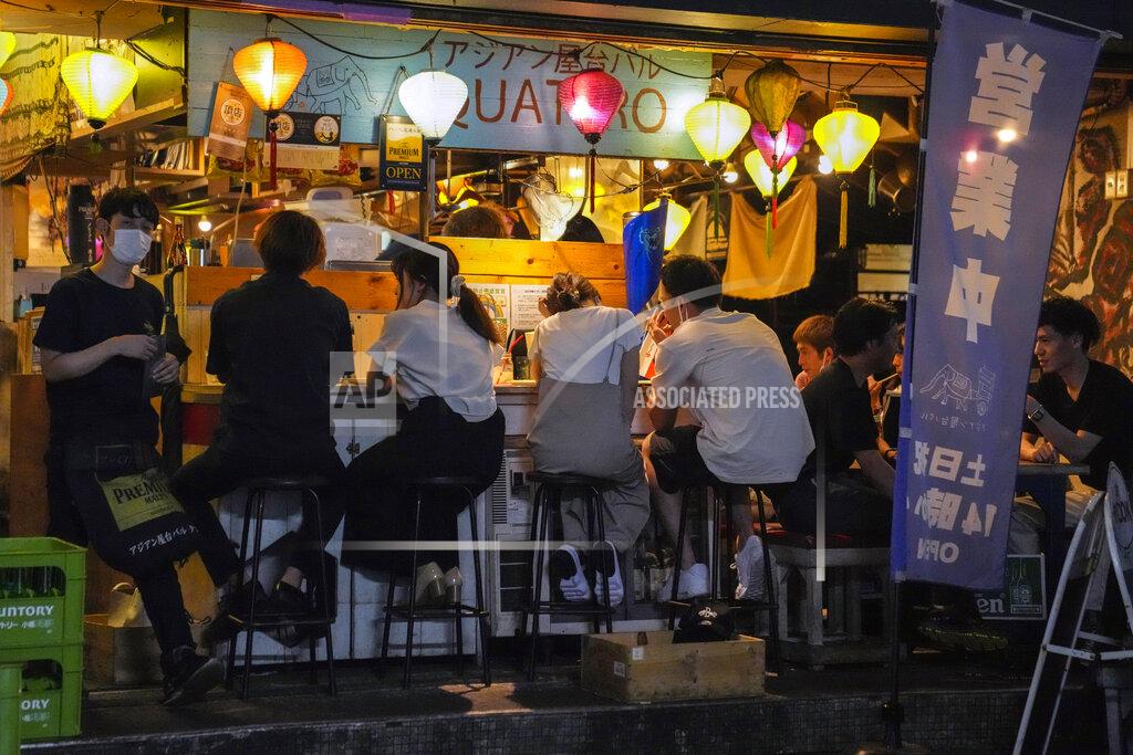 Kiichiro Sato People gather at a bar after government imposed 8 p.m. closing time for restaurants and bars under Tokyo's fourth state of emergency Saturday, July 17, 2021, in Tokyo. The latest state of emergency has asked restaurants and bars to close by 8 p.m., if not entirely. This has pushed people to drink outside, although many bars remain open and bustling with customers who are defying the rules and expressing frustration and indifference. (AP Photo/Kiichiro Sato)