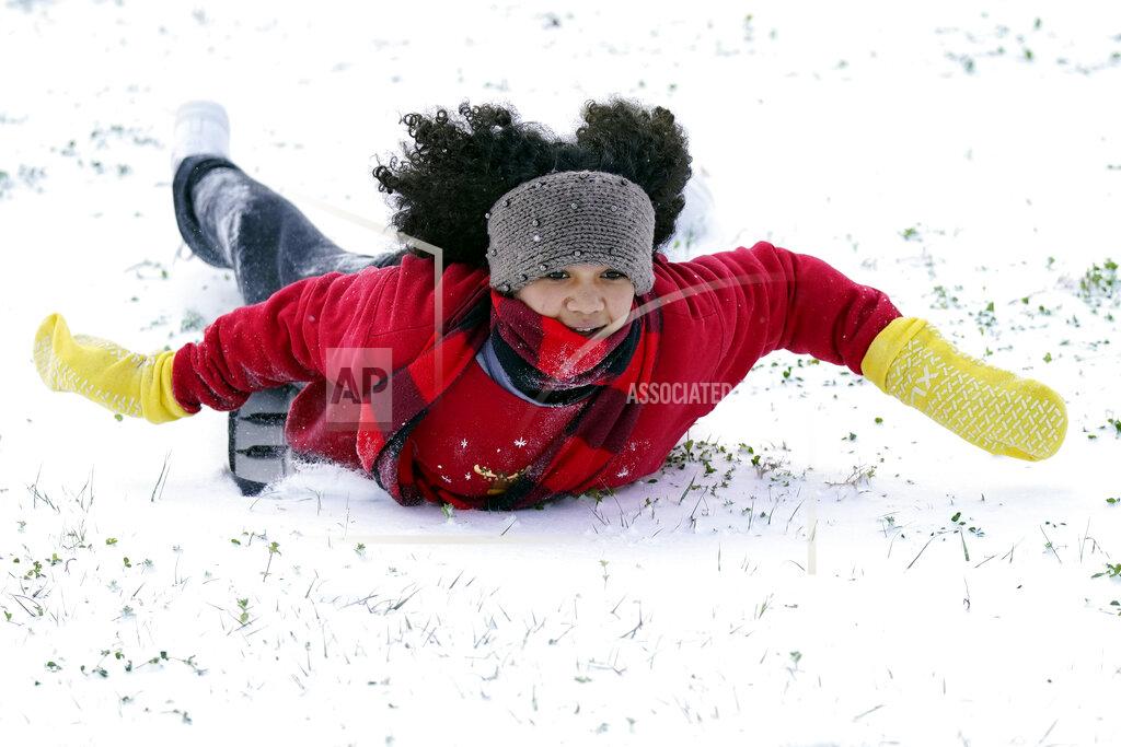 David J. Phillip Alyssa Remi, 12, slides down a snow covered hill Monday, Feb. 15, 2021, in Houston.A winter storm dropping snow and ice sent temperatures plunging across the southern Plains, prompting a power emergency in Texas a day after conditions canceled flights and impacted traffic across large swaths of the U.S. (AP Photo/David J. Phillip)