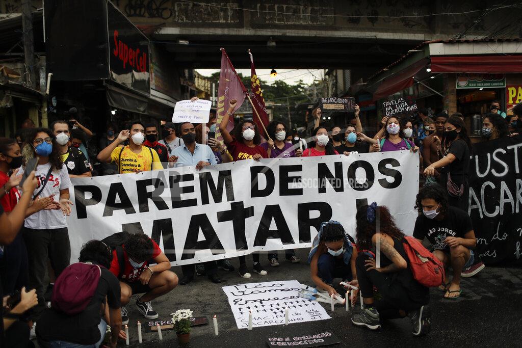 Silvia Izquierdo Activists and victim's relatives light candles and hold the Portuguese message: "Stop killing us" the day after a deadly police operation in the Jacarezinho favela of Rio de Janeiro, Brazil, Friday, May 7, 2021. A bloody, hours-long gunbattle here echoed into Friday, with authorities saying the police mission killed two dozen criminals while residents and activists claimed human rights abuses. (AP Photo/Silvia Izquierdo)