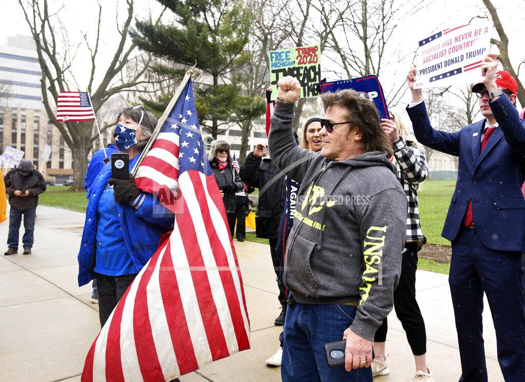 Rallygoers protest against Michigan Gov. Gretchen Whitmer's stay-at-home order at the state Capitol on Wednesday, April 15, 2020, in downtown Lansing, Mich. Hundreds of flag-waving, honking protesters drove past the Michigan Capitol to show their displeasure with Whitmer’s orders to keep people at home and businesses locked during the coronavirus outbreak. (Matthew Dae Smith/Lansing State Journal via AP)