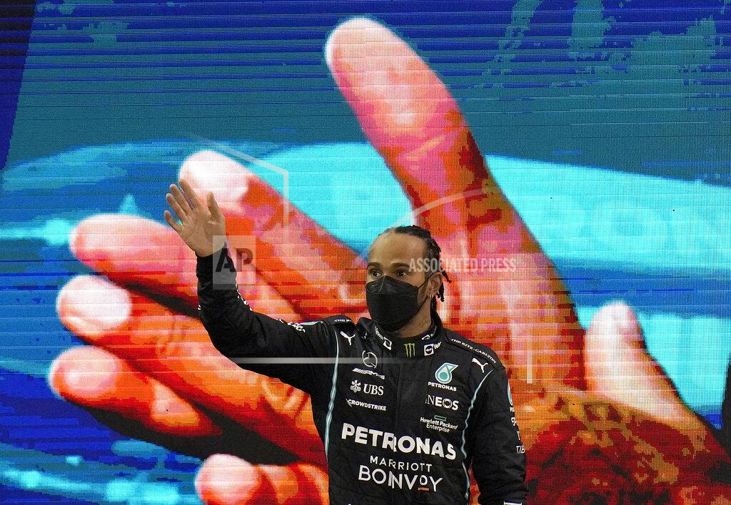 Mercedes driver Lewis Hamilton of Britain waves as he walks onto the podium after finishing second in the Formula One Abu Dhabi Grand Prix in Abu Dhabi, United Arab Emirates, Sunday, Dec. 12. 2021. Max Verstappen ripped a record eighth title away from Lewis Hamilton with a pass on the final lap of the Abu Dhabi GP to close one of the most thrilling Formula One seasons in years as the first Dutch world champion. (AP Photo/Hassan Ammar)