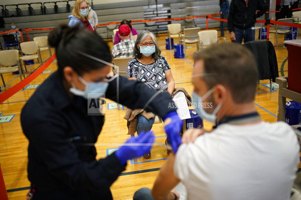 FILE - In this Feb. 17, 2021, file photo, people receive the COVID-19 vaccine at a vaccination site in Las Vegas. Coronavirus management officials acknowledged Wednesday, March 10, 2021, that some vaccination appointment slots are going unused in Las Vegas, and that more doses are available than are being administered at the area's two largest mass vaccination sites. (AP Photo/John Locher, File)