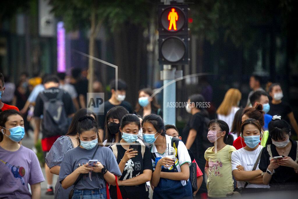 Mark Schiefelbein People wearing face masks to protect against the coronavirus wait to cross an intersection in Beijing, Wednesday, July 29, 2020. China reported more than 100 new cases of COVID-19 on Wednesday as the country continues to battle the outbreak in Xinjiang. (AP Photo/Mark Schiefelbein)