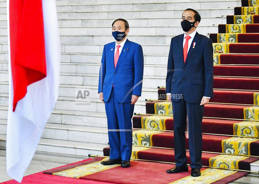 Laily Rachev In this photo released by Indonesian Presidential Palace, Japanese Prime Minister Yoshihide Suga, left, and Indonesian President Joko Widodo listen to the national anthems during their meeting at the Presidential Palace in Bogor West Java, Indonesia, Tuesday, Oct 20, 2020. (Laily Rachev/Indonesian Presidential Palace via AP)