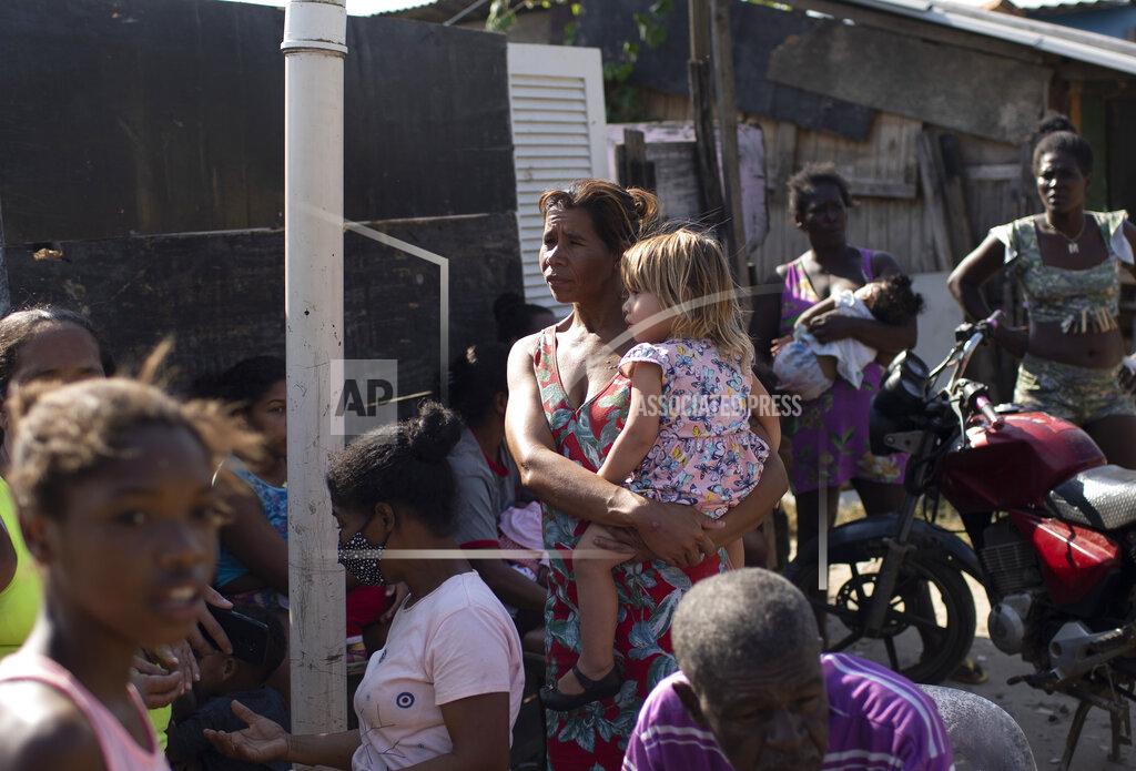 Silvia Izquierdo Women and children wait for donated food distributed by the the Covid Without Hunger organization in the Jardim Gramacho slum of Rio de Janeiro, Brazil, Saturday, May 22, 2021. Inflation is climbing at its fastest pace since 2016, at 6.8%, but over the past 12 months the cost of staple foods rose between 18% and 57%. (AP Photo/Silvia Izquierdo)